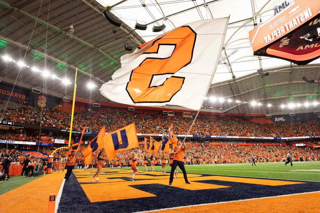 Syracuse University flag being waved on stadium JMA Wireless stadium field.